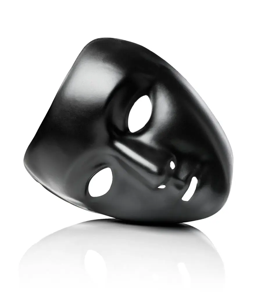 A black, shiny mask with empty eye holes and a smooth surface, positioned slightly tilted, casting a soft reflection on a white background, reminiscent of the sleek designs in motorsport.